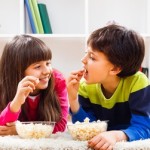 37673747 - little girl and little boy enjoy eating popcorn at home.